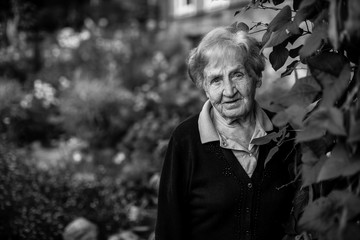 An elderly woman in the garden. Black and white portrait.