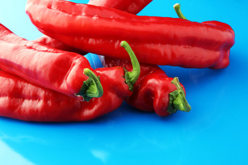 fresh and tasty red bell peppers on blue. background