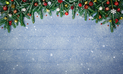 Fir Branches and Christmas Ornament on snowy blue wood plank