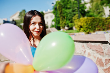 Naklejka premium Gorgeous brunette girl at street of city with balloons at hands.