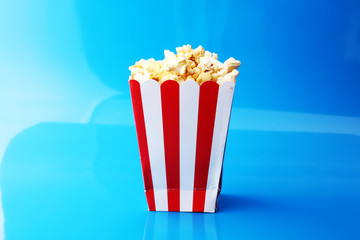 Paper cup in red and white with popcorn on color background