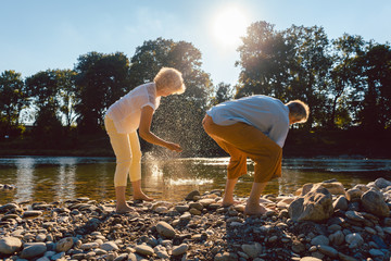 Senioren Frau und Mann fitschen Steine am Fluss im Wasser