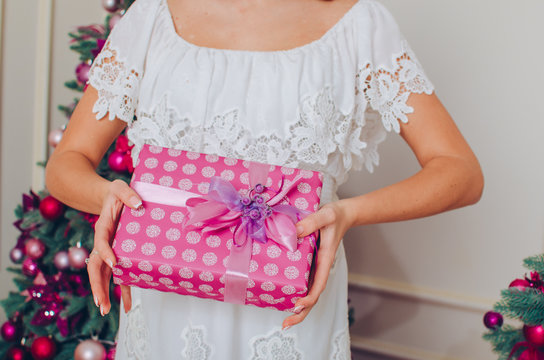 Happy young woman with christmas present in her hands on the Christmas tree