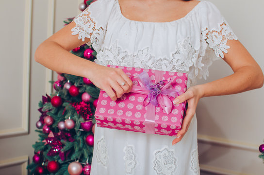 Happy young woman with christmas present in her hands on the Christmas tree