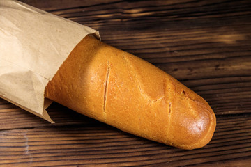 French baguette in paper bag on wooden table