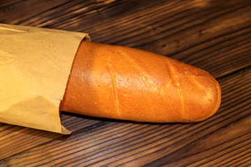 French baguette in paper bag on wooden table