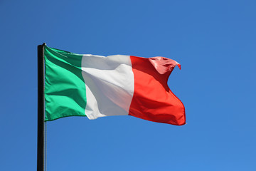 Big Italian flag waving in blue sky