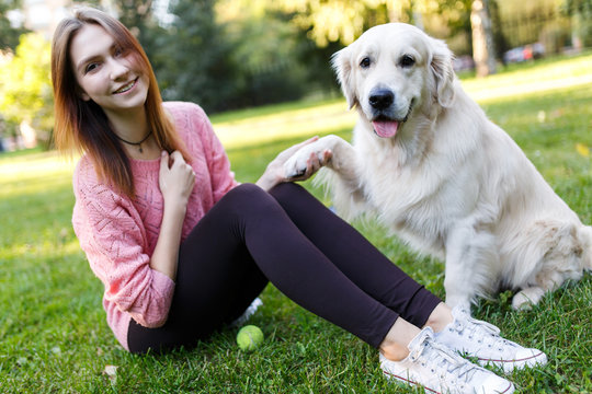 Photo of brunette with ball and dog sitting on lawn