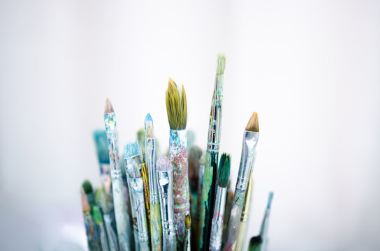 Various dirty paintbrushes on a gray background