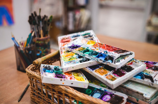 Set of watercolor paints in basket. Creative studio