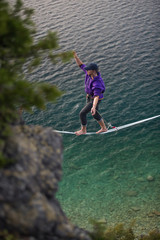 Fototapeta premium Man walking a high line slack line high above water