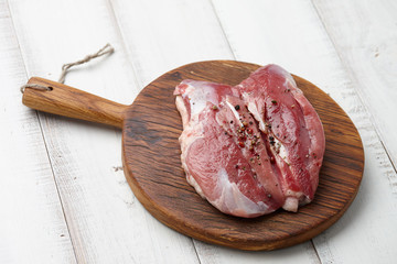 Raw duck breast or fillet steak with peppercorns and spices on cutting board on white wooden table