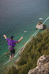 Man walking a high line slack line high above water