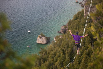 Man walking a high line slack line high above water