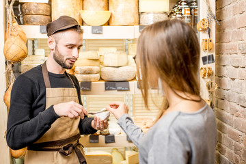 Salesman with a woman customer choosing a cheese for buying at the food store