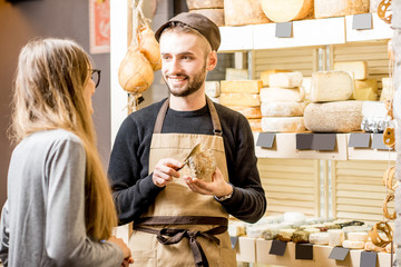 Salesman with a woman customer choosing a cheese for buying at the food store