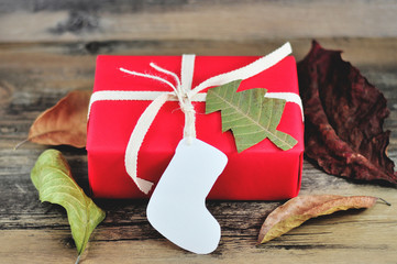 Christmas gift wrapped by red paper tied the box by Light Brown Cotton Twill Tape with white paper tag card sock shape