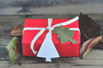 Christmas gift wrapped by red paper tied the box by Light Brown Cotton Twill Tape with white paper tag card pine tree shape