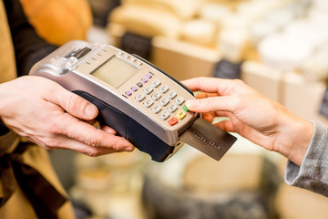 Woman paying with card in the food store. Close-up view on the terminale and card