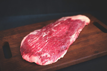 raw flank beef on a wooden Board
