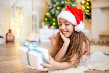 Obraz na płótnie Canvas Happy little girl smiling with gift box near the Christmas tree. Christmas concept.