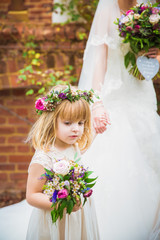 The little beautiful girl going with the bride and holding her hand outdoors