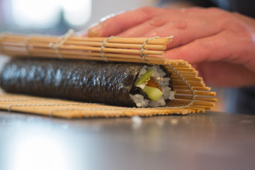 Making  sushi roll with salmon, rice, cucumber and nori. closeup
