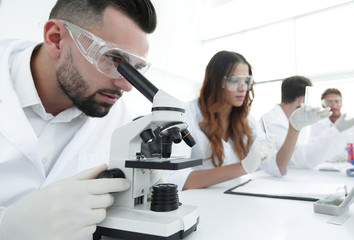 male laboratory technician looking at samples in the microscope