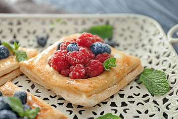 Tasty pastry with berries on tray, closeup