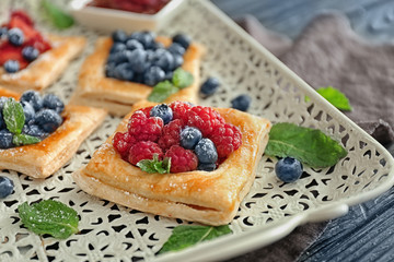 Tasty pastries with berries on tray, closeup