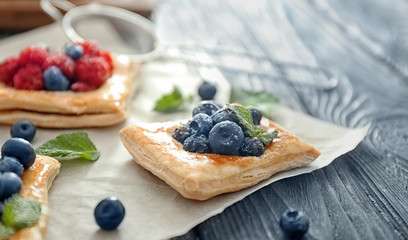 Parchment with tasty berry pastries on table