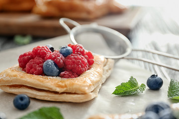 Tasty pastry with berries on parchment, closeup