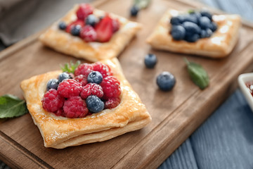 Tasty pastry with berries on wooden board, closeup