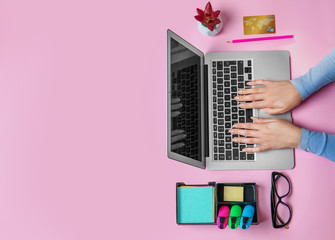 Young woman using laptop for online shopping on color background