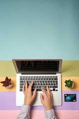 Young woman using laptop for online shopping on color background