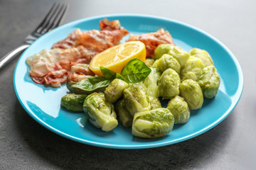 Plate with roasted Brussel sprouts and bacon on table