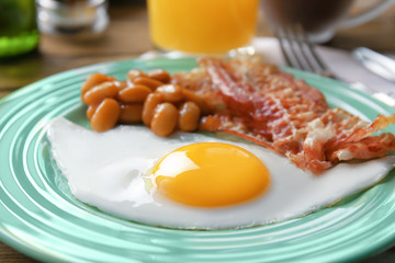 Plate with fried egg, bacon and beans, closeup