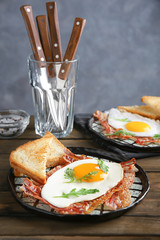 Plate with fried egg and bacon on wooden table