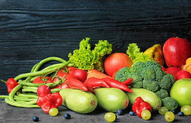 Composition with different fruits and vegetables on table against dark wooden background