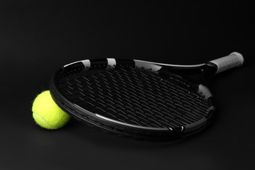 Tennis racket and ball on dark background