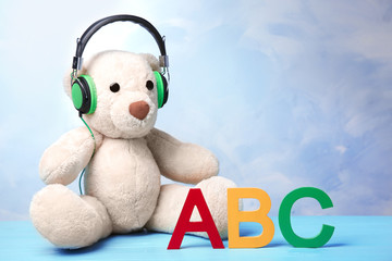 Toy with headphones on table against color wall. Baby songs concept