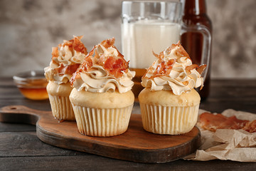 Tasty cupcakes with bacon on wooden board