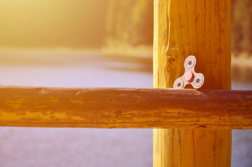 A wooden spinner lies on a wooden bar against a background of river water