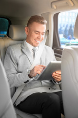 Man in formal wear with tablet computer in car