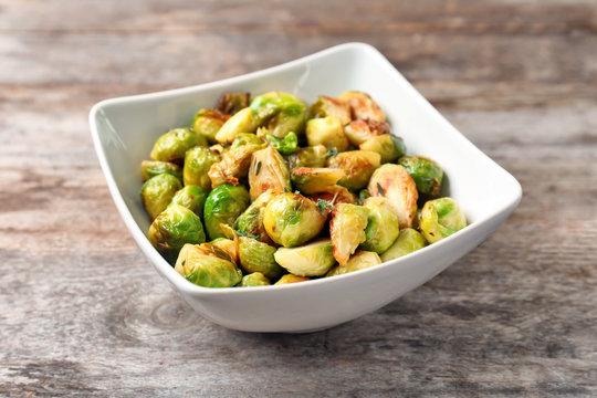 Bowl with roasted brussel sprouts on wooden background