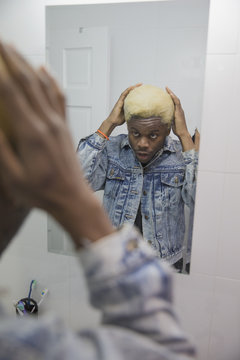 A young man fixing his hair in the bathroom