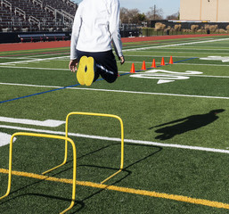 Jumping over yellow mini hurdles on a sunny day
