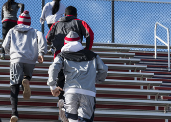 Boys and girls running up bleachers on a cool sunny day