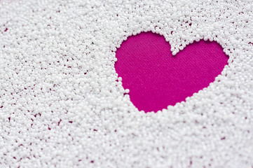 Heart on a bright pink fabric in the form of a space of white beads. Close-up with soft focus. Love concept.
