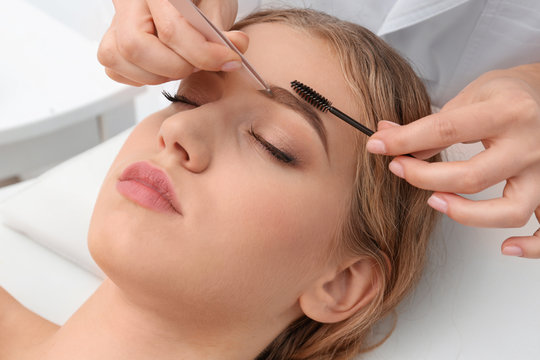 Fototapeta Young woman having eyebrow correction procedure in beauty salon